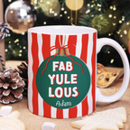 Mug with 'FAB YULE LOUS' text and Christmas decorations in the background