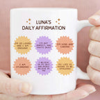 Mug with 'LUNA'S DAILY AFFIRMATION' text and colorful affirmations held by a person.