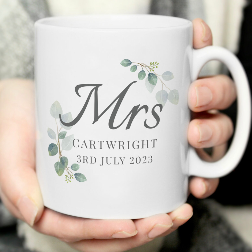 White mug with 'Mrs' and personalized text held by a person