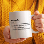 Person holding a mug with 'Hannah' definition text against a yellow background