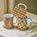 Three patterned mugs on a lace doily with a blurred background