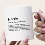 White mug with Scorpio definition text held by a hand with pink nail polish.