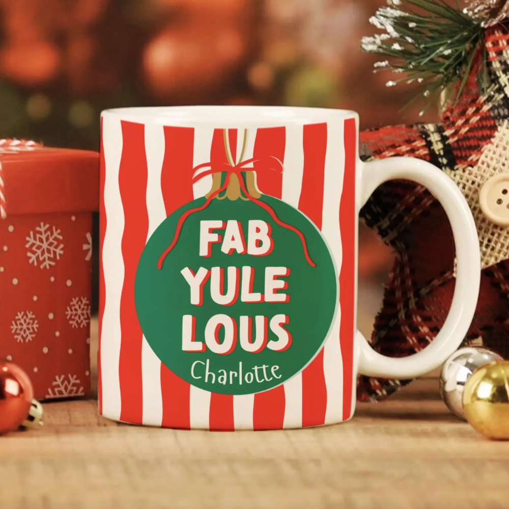 Christmas-themed mug with 'FAB YULE LOUS' text and decorative elements on a festive background.