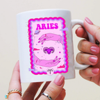 Mug with Aries zodiac design held by a person with pink nail polish.