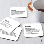 Set of four coasters with zodiac-themed text on a wooden surface with a mug.