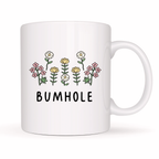 White mug with floral design and 'BUMHOLE' text on a white background