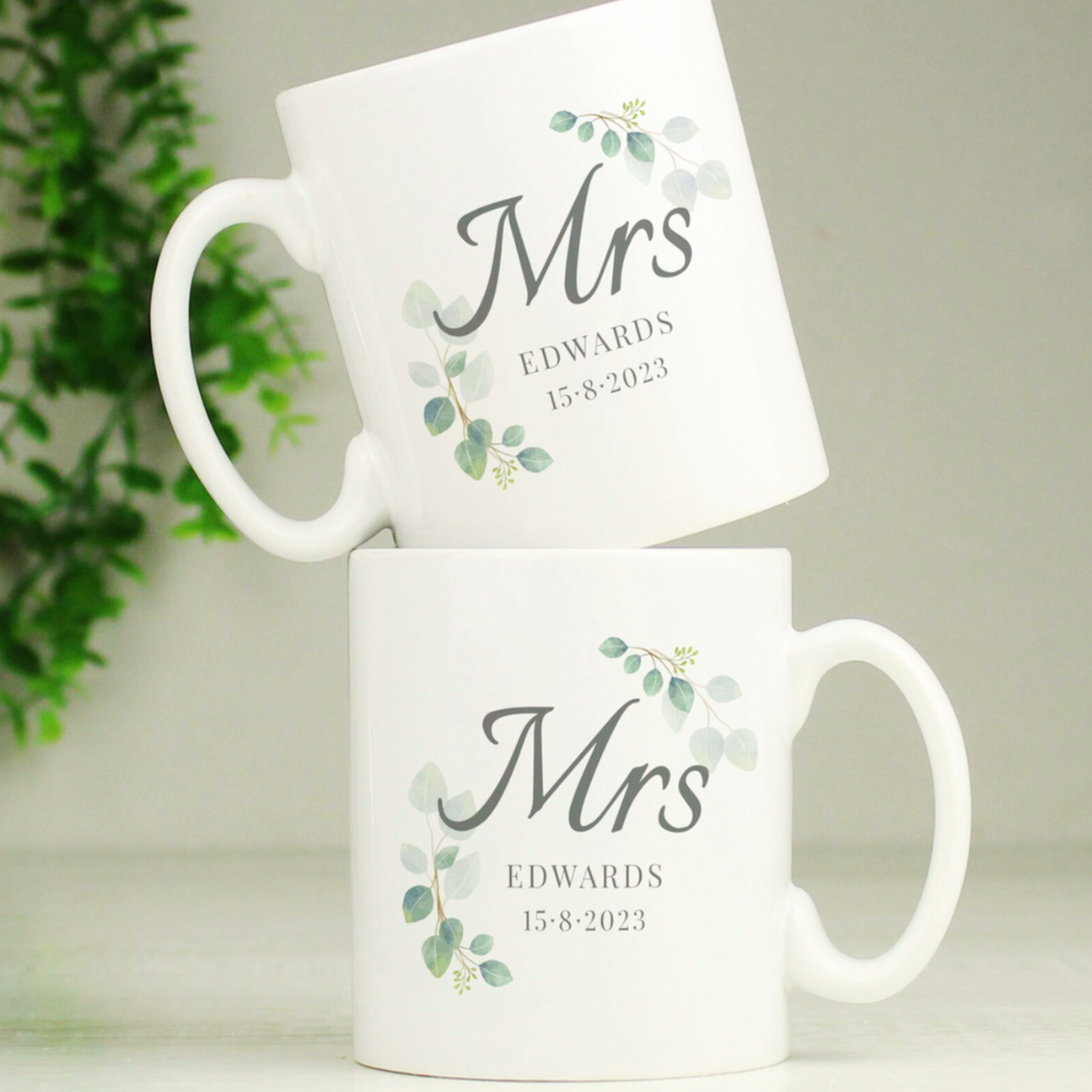 Two white mugs with 'Mrs' and personalized text on a light background