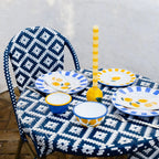 Lemon Stripe Dinner Candle in a yellow lemon ceramic candleholder on a teal striped tablecloth against a yellow wall