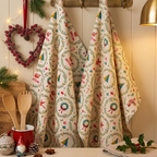 Festive Christmas cotton tea towel hanging in a cosy kitchen with wreaths, robins and Christmas trees