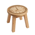 A small round wooden stool with four legs, featuring an engraved clock face design on the seat with the text 'MRS. HENDERSON'S LITTLE TIME OUT TO REST, PLEASE REMEMBER' and clock hands.