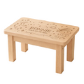 A small wooden children's stool or table with engraved personalisation reading 'RONNIE' and 'touch for the stars,' shown in a nursery-like room on a star-patterned rug.