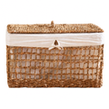 A rectangular woven storage basket with a lid, made from natural tan seagrass or wicker, lined with a cream fabric liner and tied with a small bow at the front.