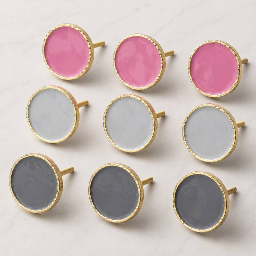 Nine round gold-tone stud earrings with flat circular faces in pink, white, and gray, arranged in a 3-by-3 grid on a light marble surface.