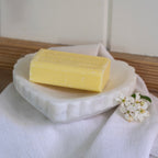 Marble Heart Dish styled on a white linen cloth with a yellow soap bar and white blossom flowers on a wooden surface