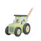 A wooden toy push tractor with a light green body, dark gray wheels, cartoon driver figures in the windows, and a natural wood push handle on a white background.