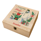 A personalized light wood keepsake box featuring a festive illustration of The Snowman, wrapped presents, greenery, and the text 'Unwrap the Magic', 'The Snowman', and 'Scarlet' on a white background.