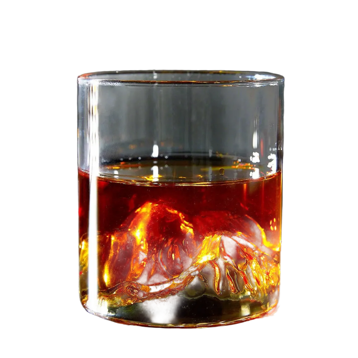 A clear rocks glass with a detailed mountain design on the bottom, filled with amber whiskey, set on a dark tabletop with a blurred background.
