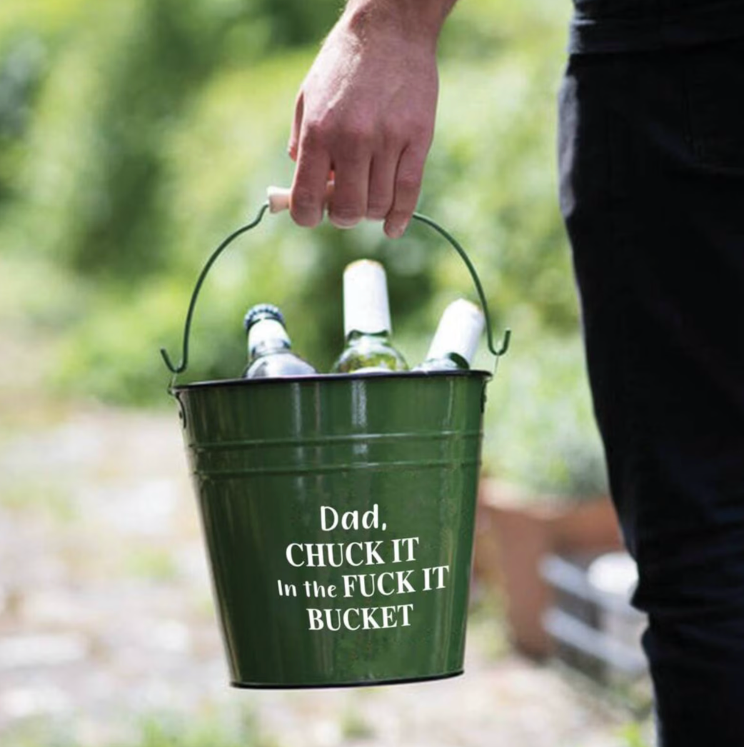 Person holding a green bucket with bottles and humorous text outdoors