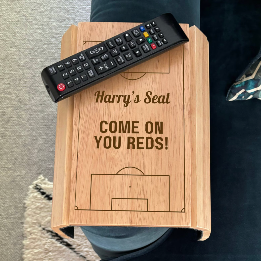 Wooden stool with 'Harry's Seat' and 'Come on You Reds!' text, remote control on top.