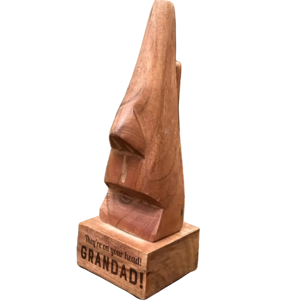 Wooden sculpture of a face on a wooden base with 'GRANDAD!' engraving, placed on a wooden surface.