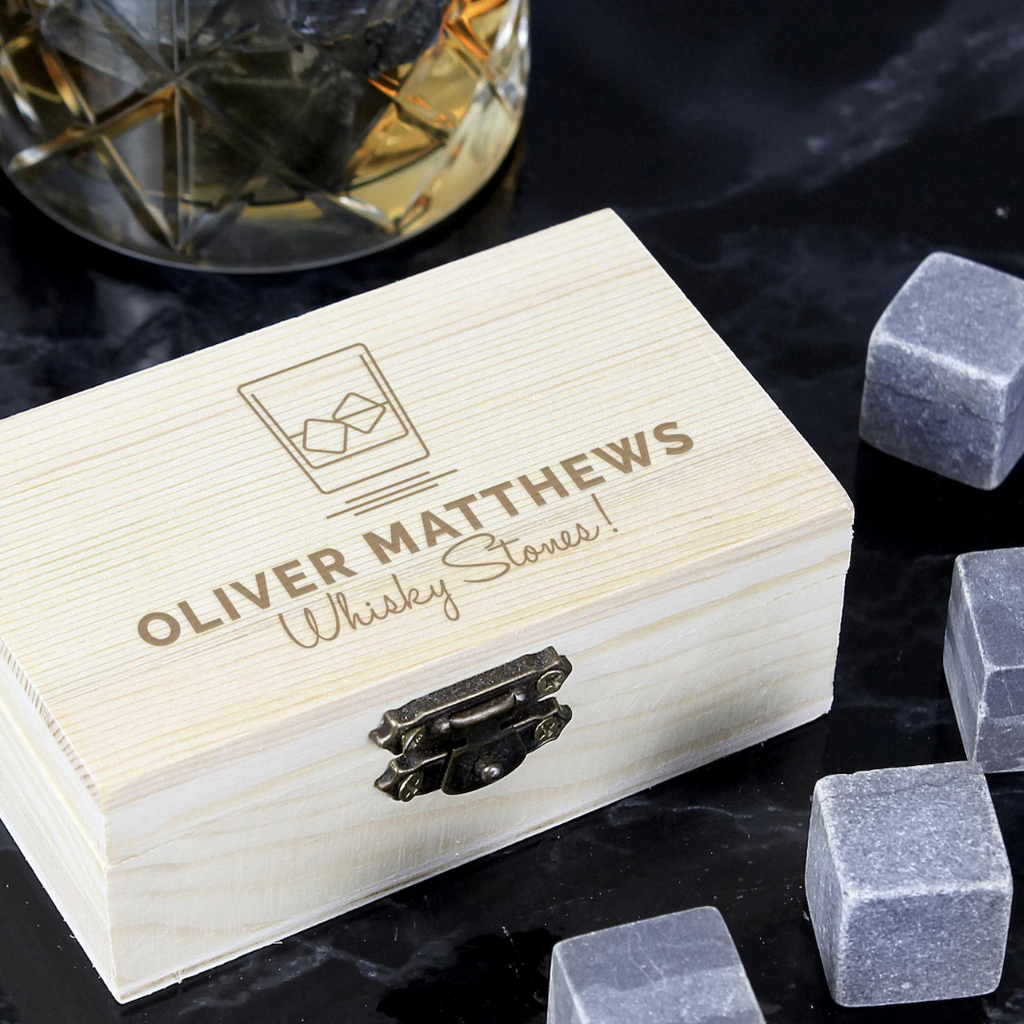 Whisky stones with a wooden box labeled 'Oliver Matthews Whisky Stones' on a dark surface.
