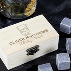 Whisky stones with a wooden box labeled 'Oliver Matthews Whisky Stones' on a dark surface.
