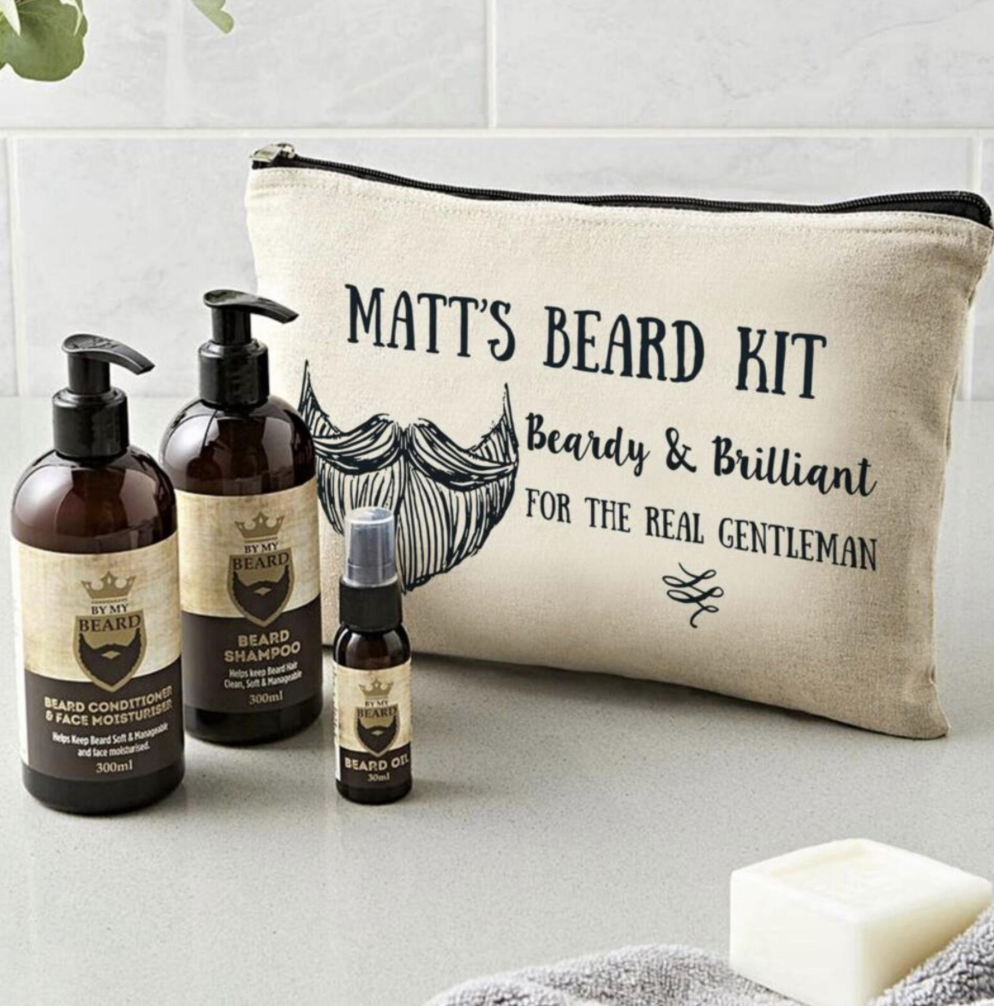 Beard care products including bottles and a pouch labeled 'Matt's Beard Kit' on a bathroom counter.
