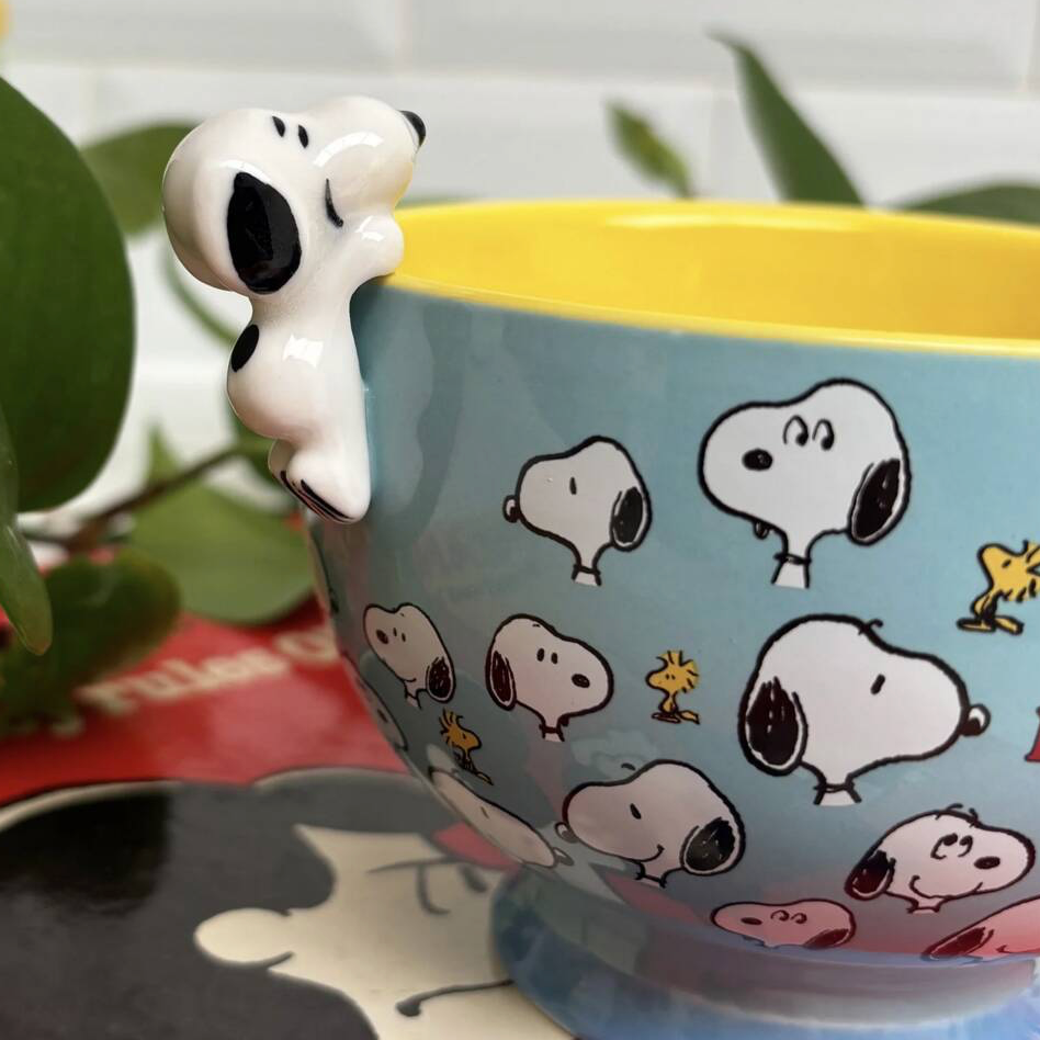 Snoopy Be Happy Cup filled with coffee on a white surface