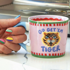 Go Get Em Tiger mug held in hand showing the tiger illustration and bold lettering on pastel pink