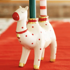 Ceramic Camel Candle Holder on a red gingham tablecloth in front of a lit Christmas tree with two taper candles