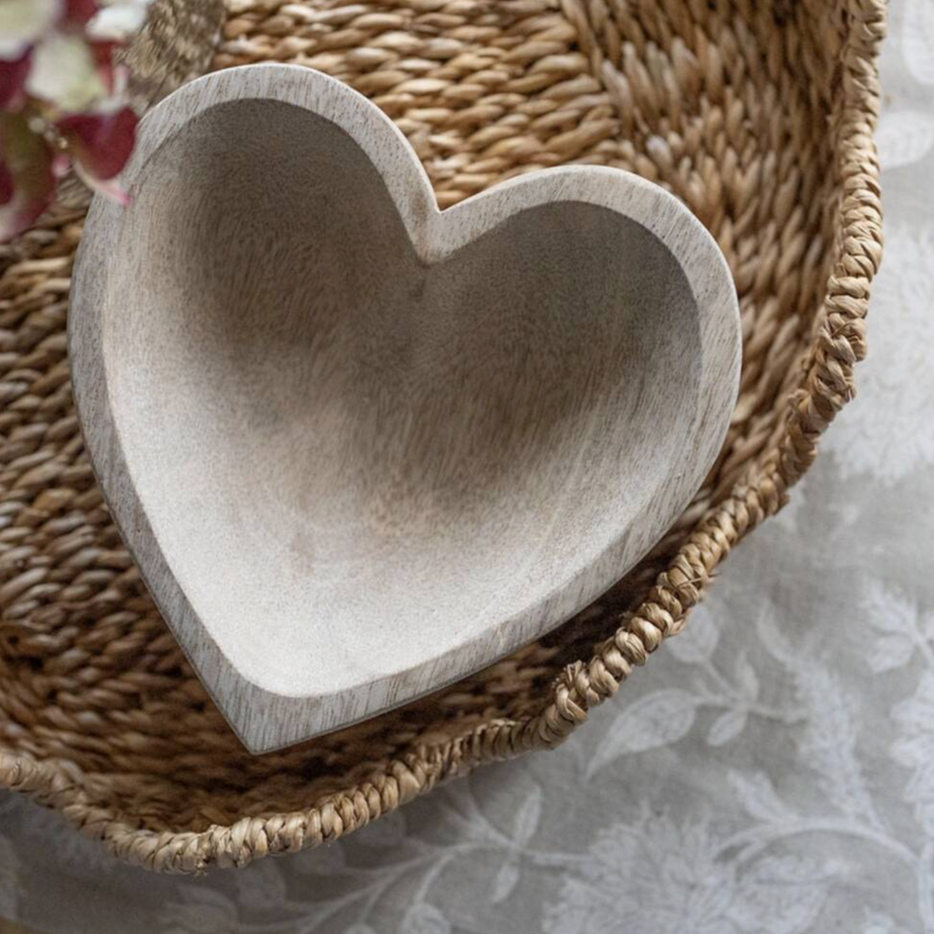 Mango Wood Heart Shaped Trinket Holder on a wicker tray with a glass vase of dried pink flowers