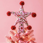 Two Sided Pom Pom Star Tree Topper showing the red and white candy stripe reverse side on a Christmas tree