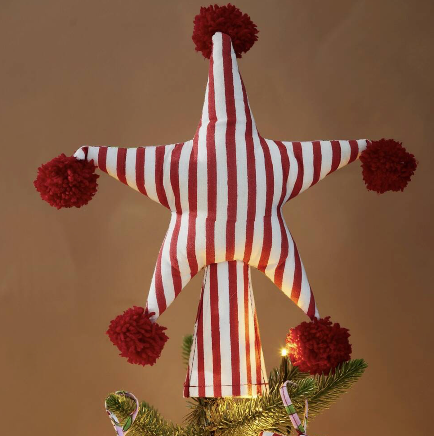 Two Sided Pom Pom Star Tree Topper with Arana floral print on a pink Christmas tree against a pink background