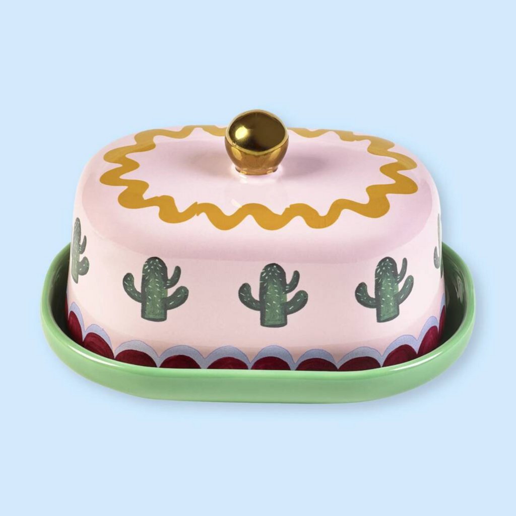 Pink And Green Cactus Design Butter Dish closed on a light blue background showing the domed lid with cactus print and gold ball handle