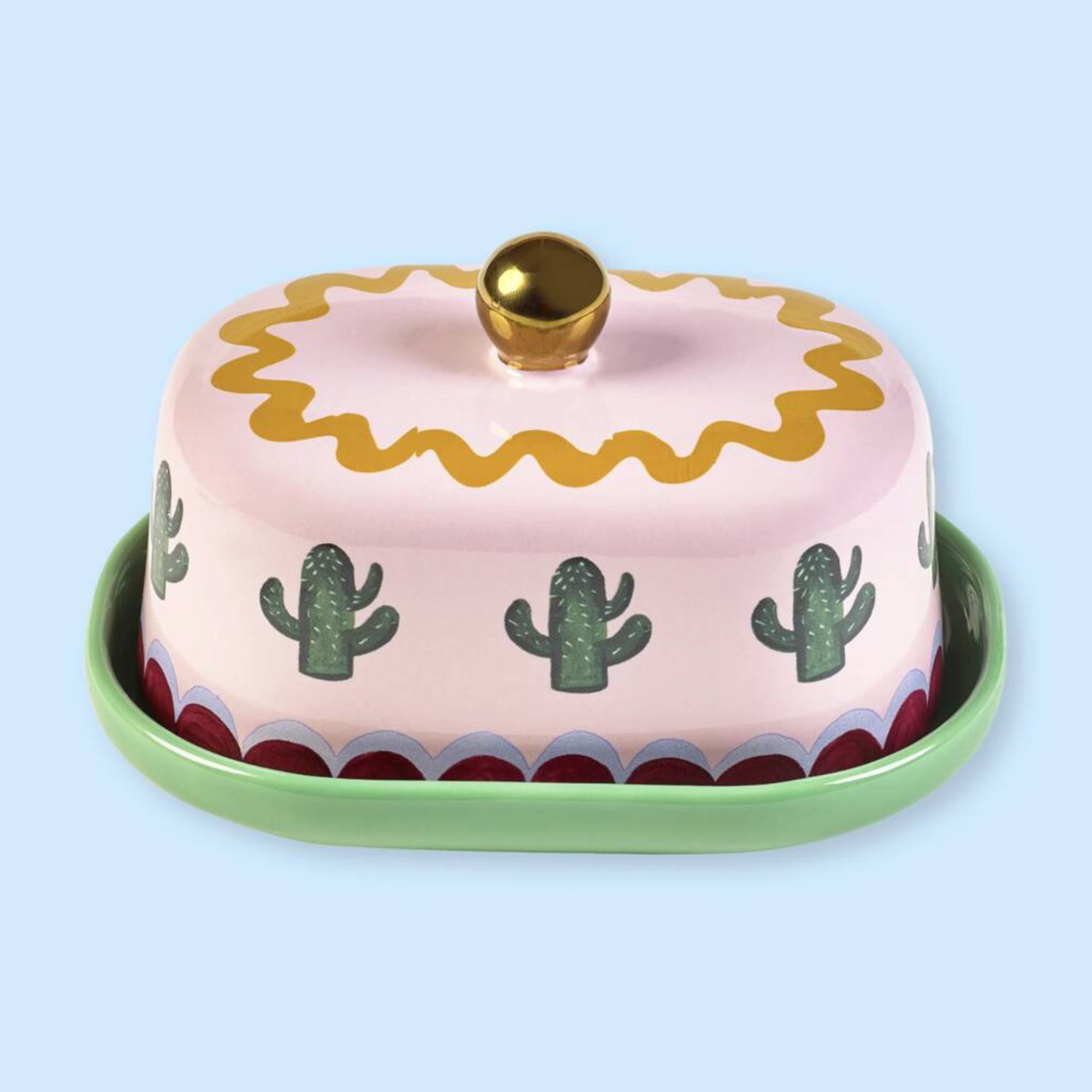 Pink And Green Cactus Design Butter Dish closed on a light blue background showing the domed lid with cactus print and gold ball handle