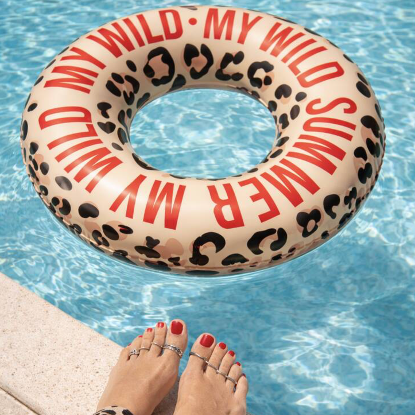 Pool Float My Wild Summer floating in a bright blue swimming pool with a woman's feet visible at the pool edge