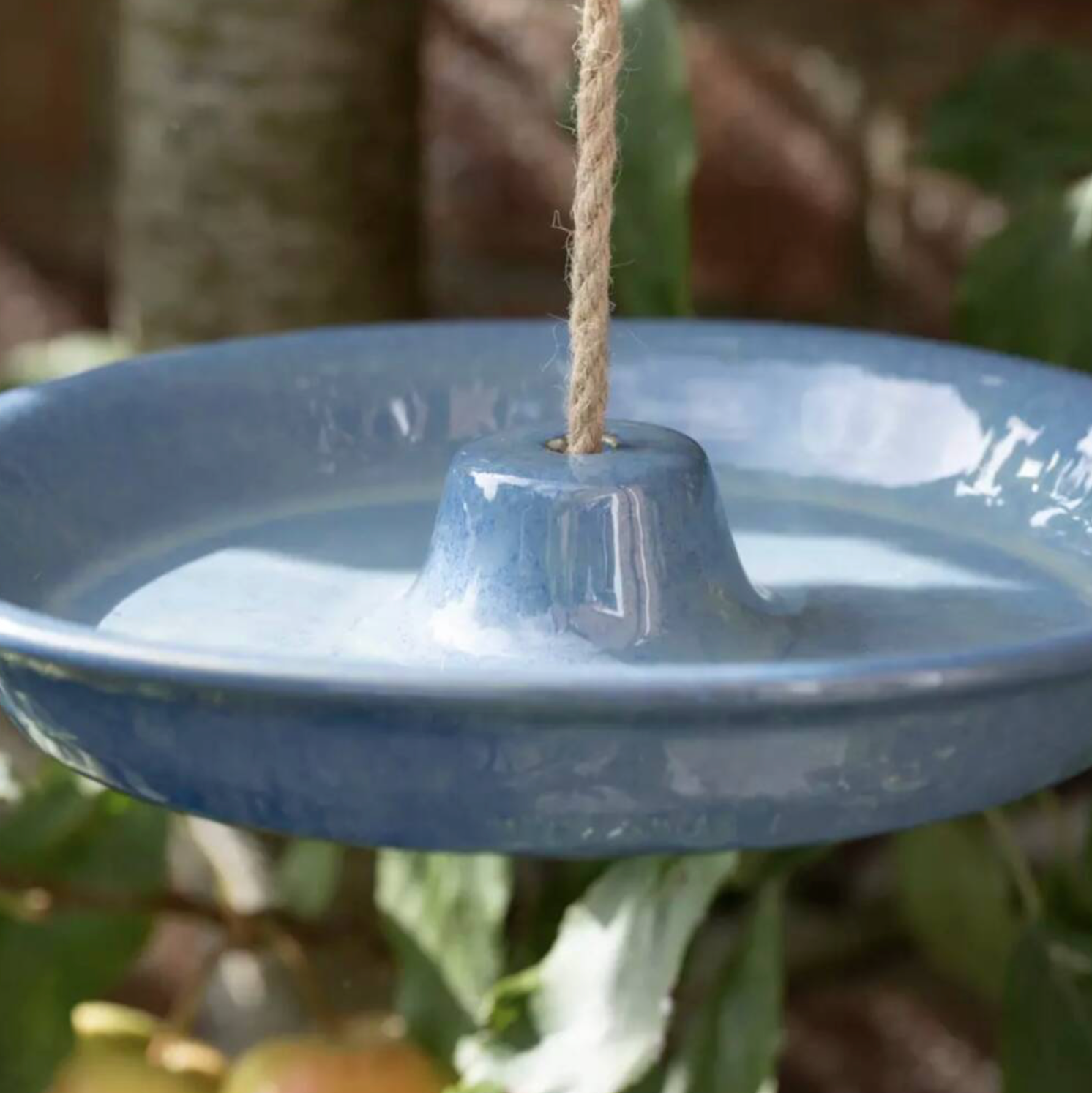 Close up of the blush pink Ceramic Hanging Bird Feeder and Bath suspended by jute rope showing the central cone and gloss glaze