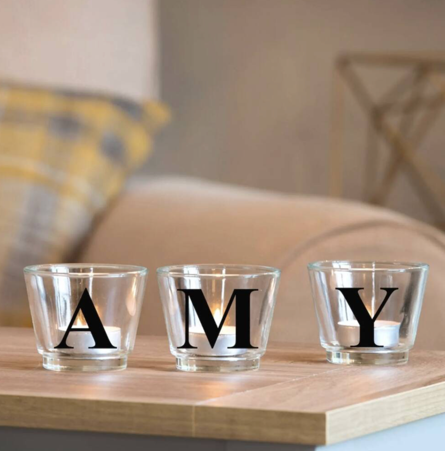Personalised Letter Glass Votives spelling AMY in black letters on a wooden board with a sofa in the background