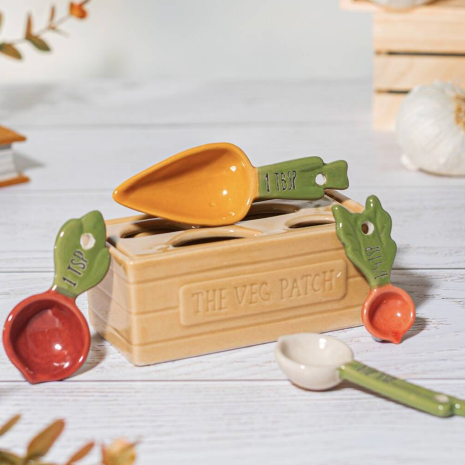 Ceramic Vegetable Patch Measuring Spoons displayed around the Veg Patch crate on a white wooden surface with dried botanicals