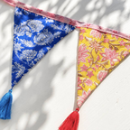 Close up of Hand Block Print Bunting With Tassels showing the blue floral and yellow floral flags with blue and red silk tassels