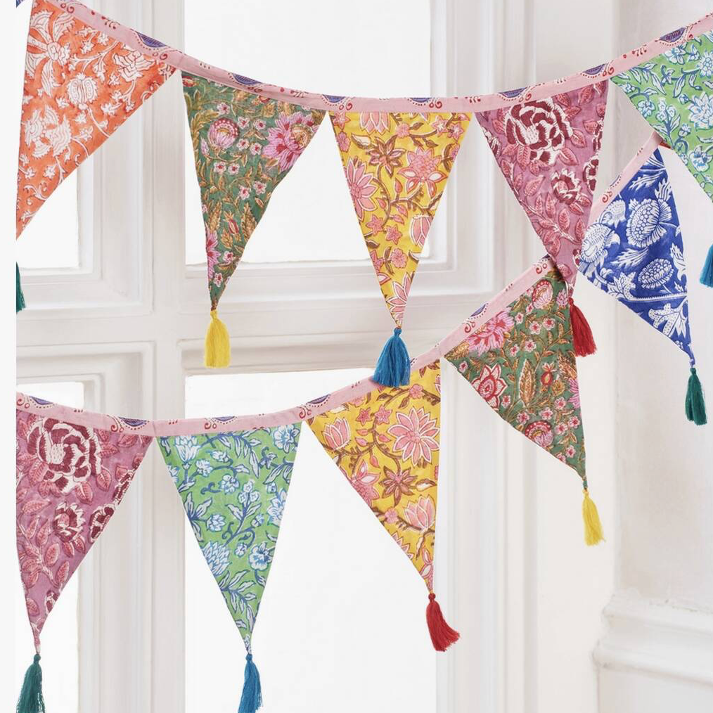 Hand Block Print Bunting With Tassels hung outdoors in a garden with pink dahlias and wildflowers in the foreground