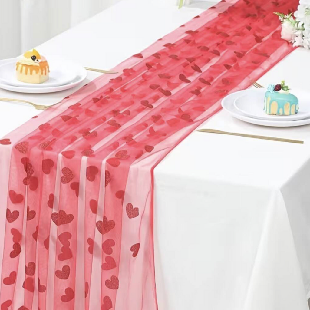 Close up of Embroidered Lace Hearts Table Runner held in a hand showing the sheer organza fabric and glitter embroidered heart detail