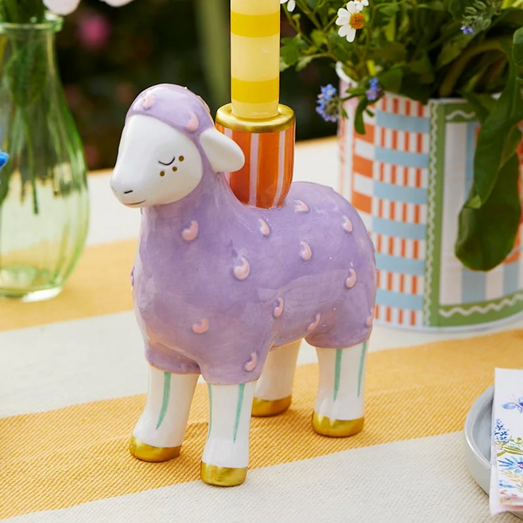 Hand Painted Lamb Ceramic Candle Holder styled on a yellow striped table runner with a yellow stripe dinner candle lit and wildflowers in background