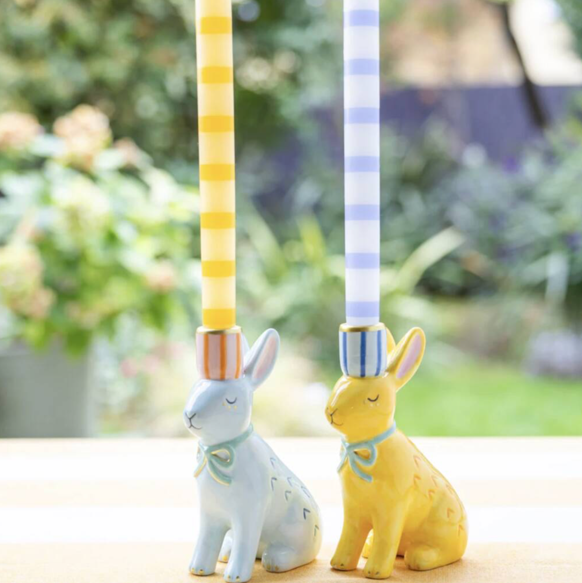 Close up of Hand Painted Bunnies Ceramic Candle Holder pair showing the sleeping faces mint green bows and striped candle sockets with candles lit