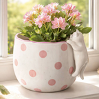 Spotty Peeking Cat Planter on a sunny windowsill filled with pink kalanchoe flowers showing the full planter and peeking cat from the side