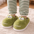 Close-up pair of fluffy green monster slippers with cartoon eyes and teeth