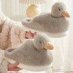 Grey duckling slippers with soft fluffy texture and duck faces held in hand