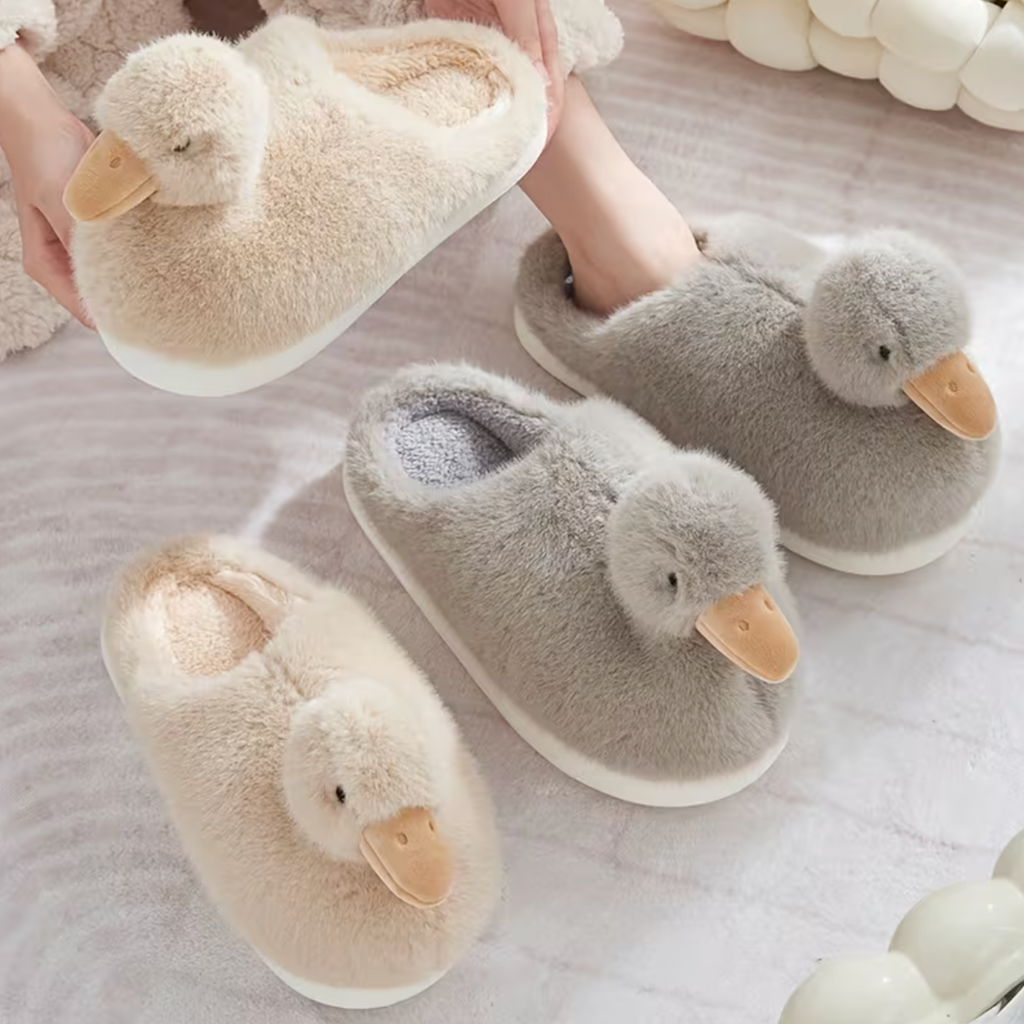 Grey duckling slippers shown in a cosy lifestyle display with cream duck slippers