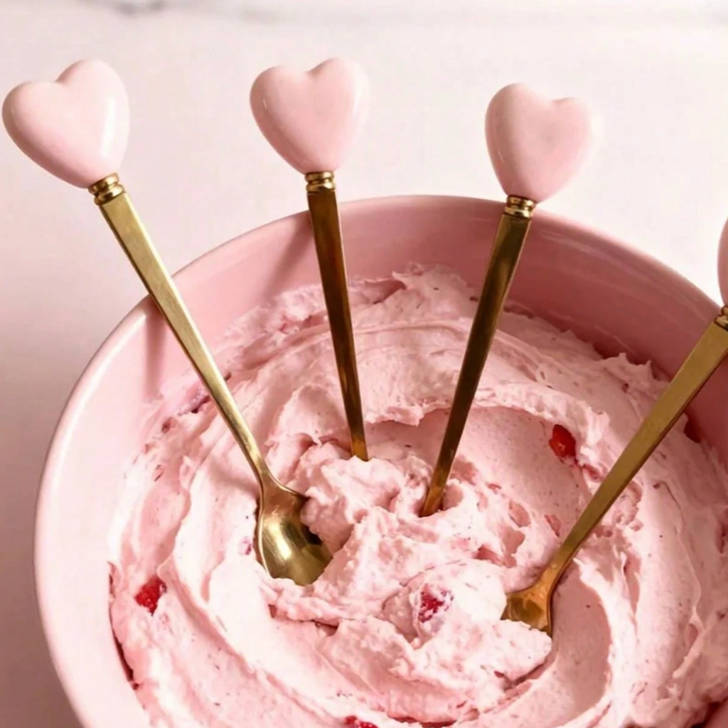 Gold heart-handle spoons arranged on a pink table setting