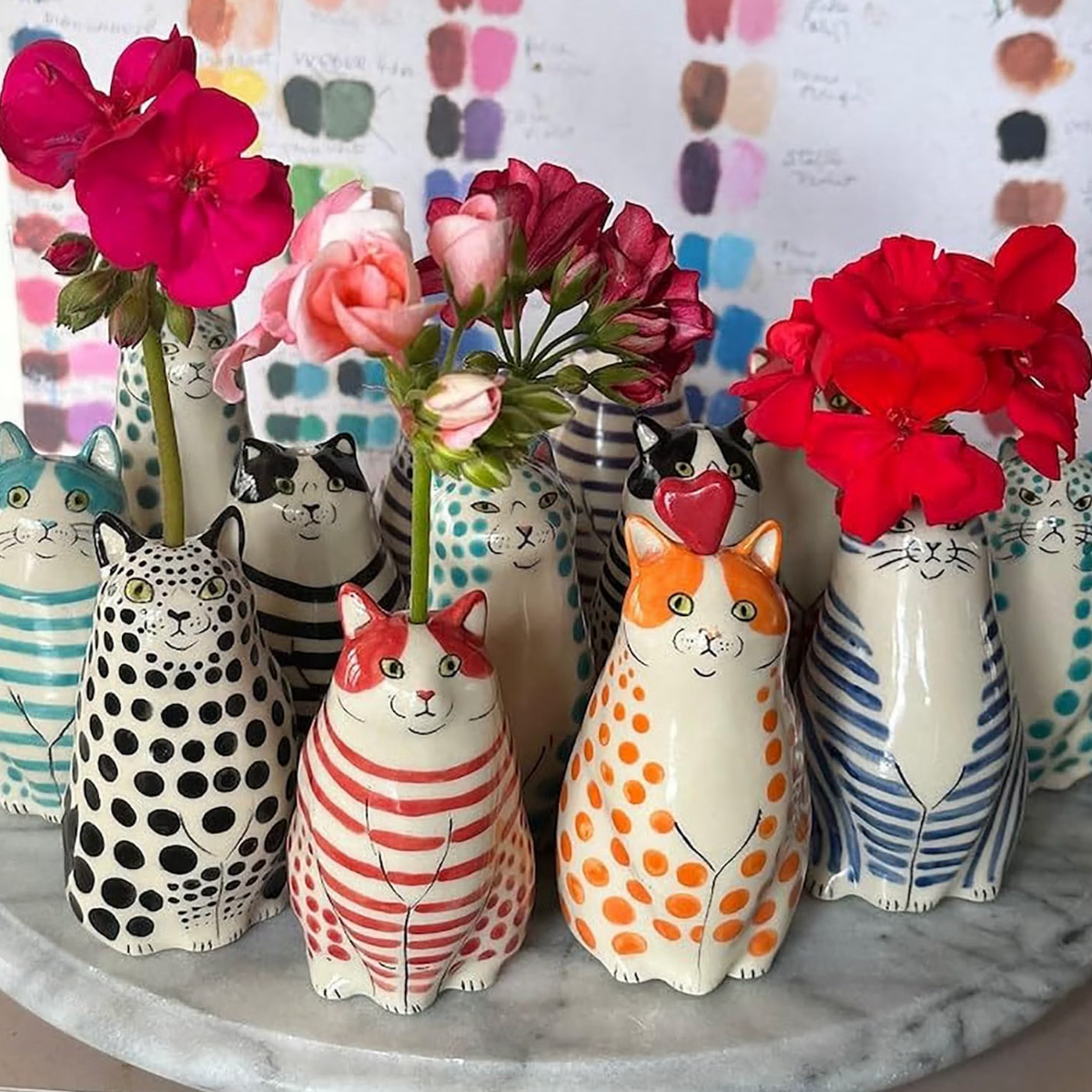 Colourful cat bud vases displayed together with flowers in a home setting